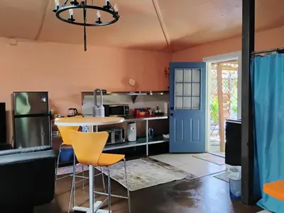 a kitchen with orange walls and a table and chairs at Ping's Tiny Home self-check in & out private in Merced