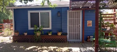 a blue house with a window and potted plants at Ping's Tiny Home self-check in & out private in Merced