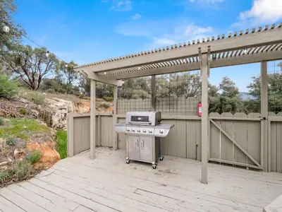 a grill on a patio with a pergola at Manzanita Hill-35 miles to Yosemite, 10 miles to Mariposa with 8 person spa in Mariposa