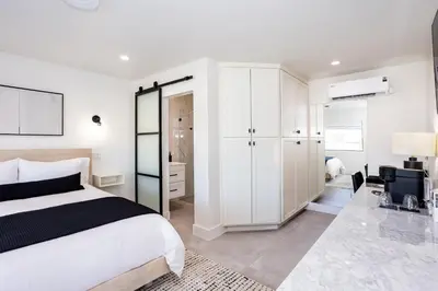a white bedroom with a bed and a desk at Hotel Bayit in Modesto