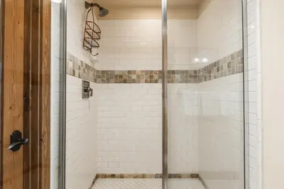 a shower with white tile and a glass door at Lodges 1156 in Mammoth Lakes