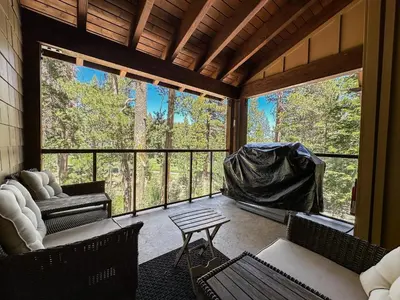 a screened in porch with a view of the forest at Woodwinds #1303 condo in Mammoth Lakes