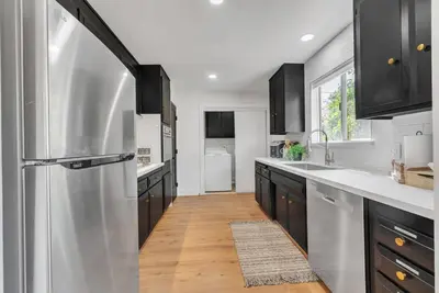 a kitchen with a stainless steel refrigerator and wooden floors at Main Street Retreat in Roseville