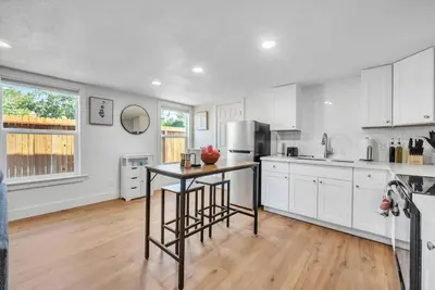 a kitchen with white cabinets and a table in it at Studio on Main Street in Roseville