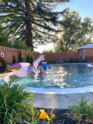 a man and a child in a pool with a inflatable shark at NEW cozy beautiful house with pool and hot tub in Fair Oaks
