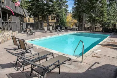 a swimming pool with chaise lounge chairs next to it at Bigwood #96 condo in Mammoth Lakes