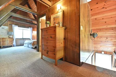 a bedroom with wooden walls and a dresser in a room at Hathaway Pines Hideaway Chalet in Hathaway Pines