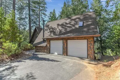 a house with two garage doors on a driveway at Hathaway Pines Hideaway Chalet in Hathaway Pines