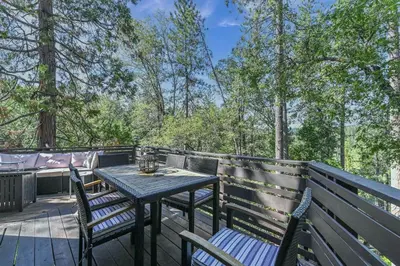 a wooden table and chairs on a deck with trees at Hathaway Pines Hideaway Chalet in Hathaway Pines