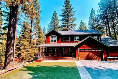 a red house with a garage in the woods at Elegant 6 Bed Sleeps 14 - Best for families w kids in South Lake Tahoe
