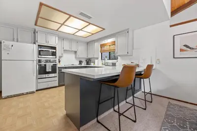 a kitchen with white appliances and a counter with stools at Sequoia Zen River House in Three Rivers