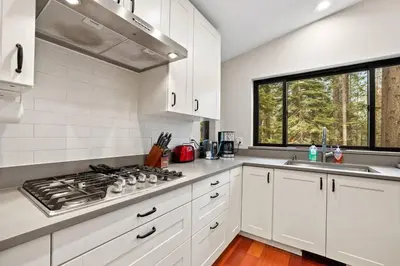 a white kitchen with a stove and a window at Mountain Pine Memories - Dogs - Hot tub - E-bikes in South Lake Tahoe