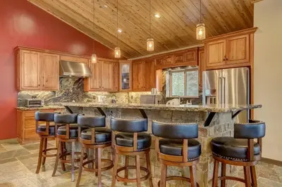 a kitchen with wooden cabinets and a bar with stools at Chateau de Navahoe - Luxury - Hot tub - Large yard in South Lake Tahoe
