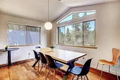 a dining room with a table and chairs and windows at Sierra Solace - Forest & Seasonal River Out Back in South Lake Tahoe