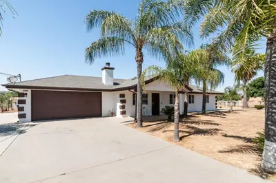 a house with palm trees in front of it at Remodeled 1 Acre Ranch Home in Madera in Madera