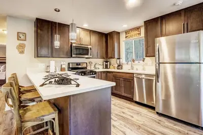 a kitchen with wooden cabinets and a stainless steel refrigerator at Bear Cub Cabin - Pets - Hot tub - Arcade Game in Mevers