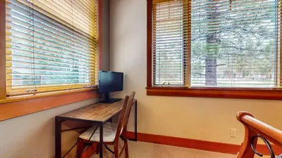a room with a desk with a television and two windows at Timbers #27 townhouse in Mammoth Lakes