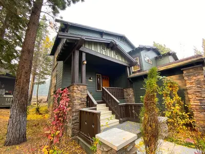 a green house with a porch and a tree at Timbers #27 townhouse in Mammoth Lakes
