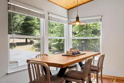 a dining room with a table and chairs and windows at Peaceful Creekside Buddha Retreat in Groveland