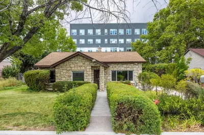 a brick house with a large building in the background at Cozy 2BR Home Near UNR with Large Deck & Parking in Reno