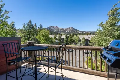 a table and chairs on a balcony with mountains at Snowcreek #793 Phase V - 3 Bedroom 3 Bath Sleeps 8 with Private 1 Car Garage in Mammoth Lakes