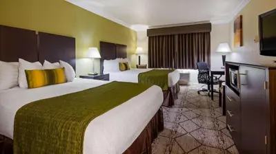 a hotel room with two beds and a flat screen tv at Best Western Executive Inn in Los Banos