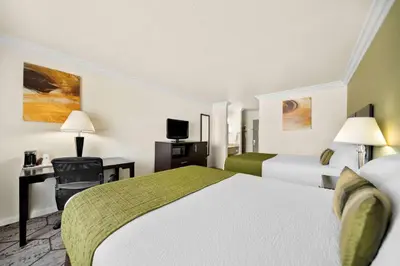 a hotel room with two beds and a desk at Best Western Executive Inn in Los Banos