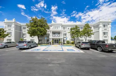 a large white building with cars parked in a parking lot at Best Western Executive Inn in Los Banos