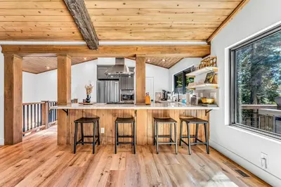 a kitchen with wooden ceilings and a large island with bar stools at Modern Mountain Luxury Retreat, Hot Tub & Grill in Carnelian Bay
