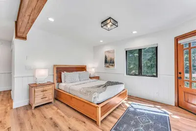 a bedroom with a bed and a table with a lamp at Modern Mountain Luxury Retreat, Hot Tub & Grill in Carnelian Bay