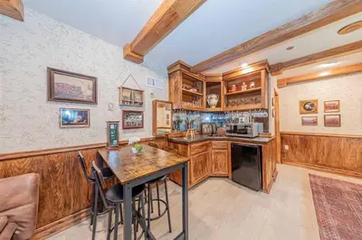 a kitchen with wooden cabinets and a table with chairs at Sunset Summit Villa 2 min from Bass Lake in Bass Lake