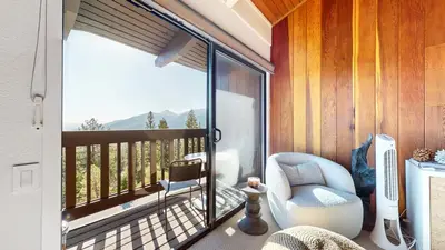 a room with a balcony with a chair and a window at Mammoth Point #117 condo in Mammoth Lakes