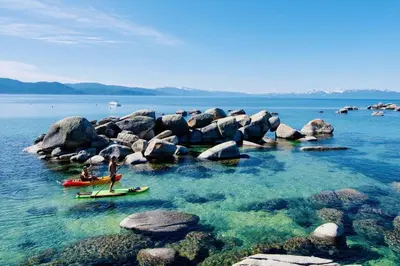 two people on surfboards in the water near rocks at Cozy and central Tahoe cabin with private hot-tub outdoor fireplaces close to slopes in Ridgewood