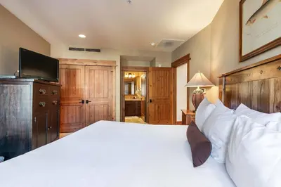 a bedroom with a large white bed and a flat screen tv at Big Horn Lodge 307 by East West Hospitality in Truckee