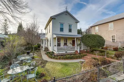 a white house with a yard with tables and chairs at Romantic Victorian Getaway The Garden in Sutter Creek