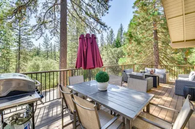 a wooden deck with a table and a umbrella at 1 Mi to Pine Mountain Lake Marina Yosemite Cabin! in Groveland