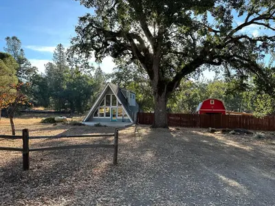 a small house with a tree and a fence at Picturesque Yosemite A-Frame in Mariposa