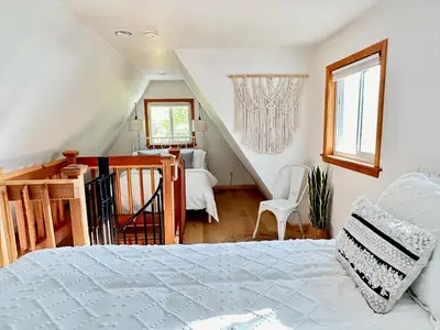 a bedroom with a white bed and a staircase at Picturesque Yosemite A-Frame in Mariposa