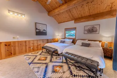 two beds in a room with wooden walls at Peppermint Falls Ranch in Ponderosa