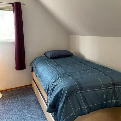 a bedroom with a bed with a blue comforter and a window at Spacious family home on the Meadow Monthly Only in South Lake Tahoe