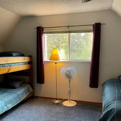 a bedroom with a window with a fan and a lamp at Spacious family home on the Meadow Monthly Only in South Lake Tahoe