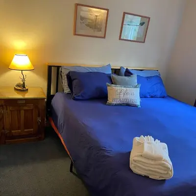 a bedroom with a bed with blue sheets and a lamp at Spacious family home on the Meadow Monthly Only in South Lake Tahoe
