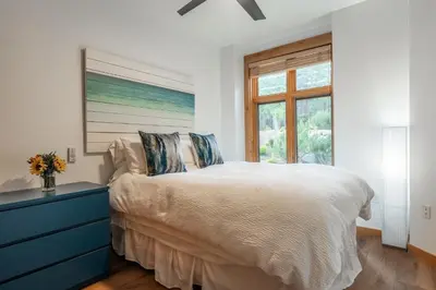 a bedroom with a bed with a blue dresser and a window at Solstice 17 in Mammoth Lakes
