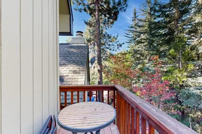 a wooden table on a balcony with a view of trees at Tahoe Tranquility in Incline Village