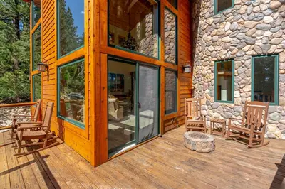 a wooden deck with two chairs and a stone building at Do not miss your chance to vacation at this five bedroom 5 bath mountain home in Incline Village