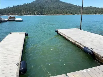 a dock on a lake with a boat in the water at Luxury Lake Home-The Bear Claw-Boat Slip-Sleeps 16 in Bass Lake