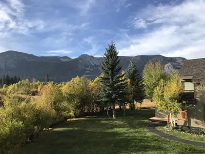 a yard with trees and a house with mountains in the background at Snowcreek II #220 condo in Mammoth Lakes