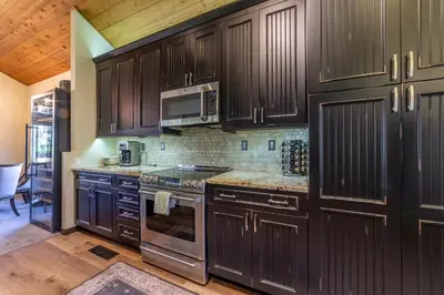 a kitchen with wooden cabinets and a stove top oven at Grand Townhome w/ Meadow Views; Private Garage in Mammoth Lakes