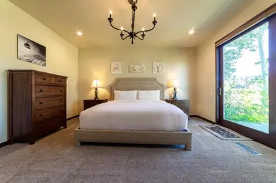 a bedroom with a large bed and a chandelier at Grand Townhome w/ Meadow Views; Private Garage in Mammoth Lakes