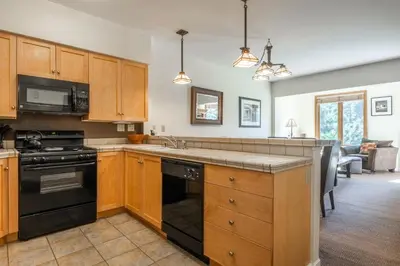 a kitchen with wooden cabinets and a black stove top oven at Mammoth Green #210 - Nearly Ski-in Ski-Out 2 Bedroom 2 Bath, Sleeps 6 on Golf Course in Mammoth Lakes